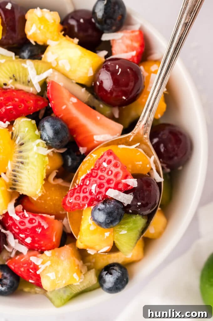 A spoonful of rainbow fruit salad, showcasing the vivid colors and fresh ingredients.