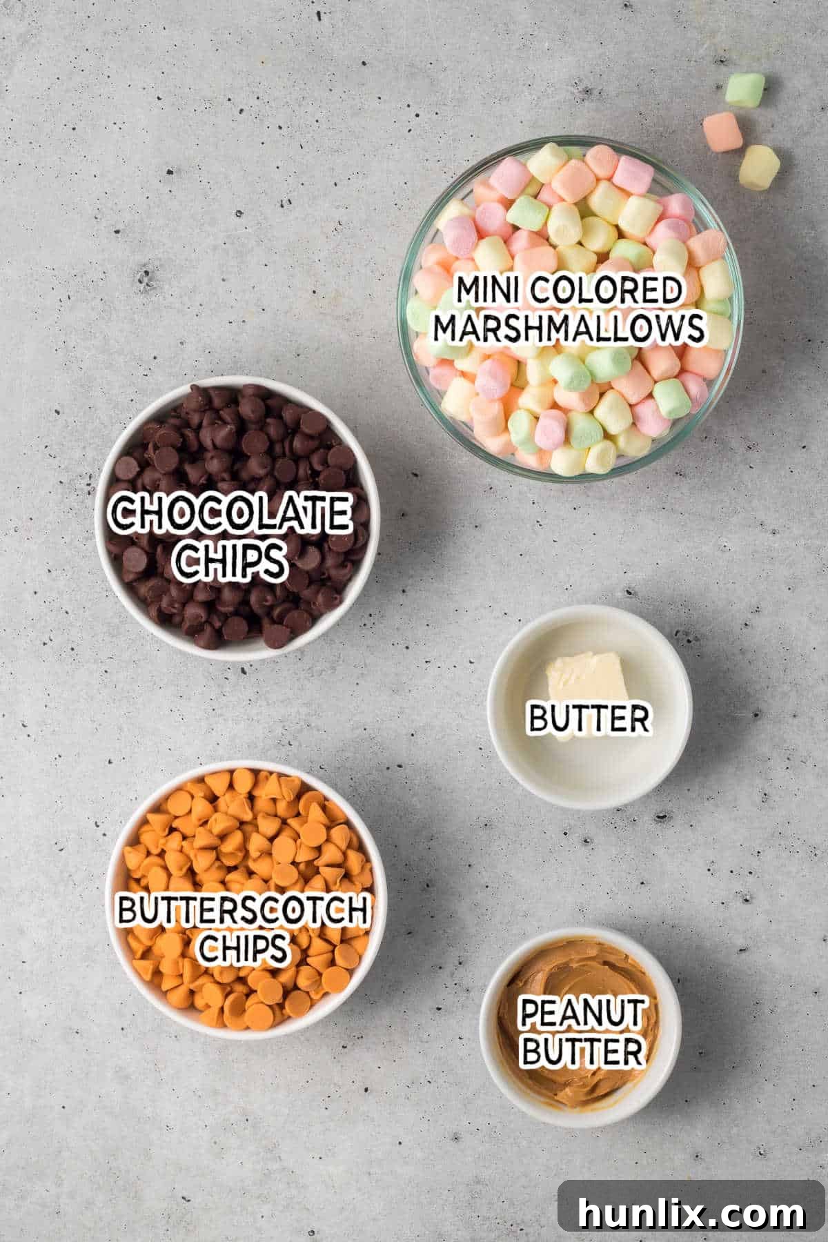 A vibrant display of ingredients for Chocolate Confetti Bars on a grey surface.