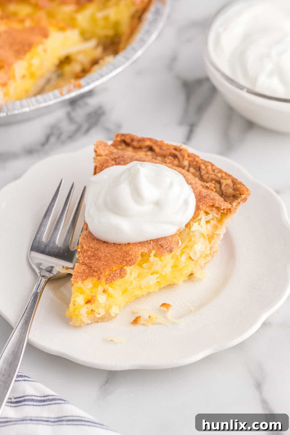 Luscious Coconut Cream Pie 6 A perfectly baked slice of coconut pie on a simple white plate, ready to be enjoyed.