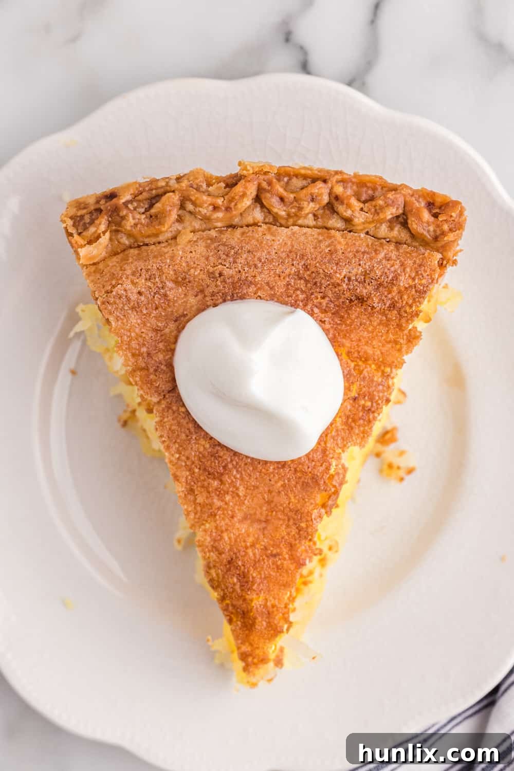 Luscious Coconut Cream Pie 9 A pristine slice of coconut pie resting on a white plate, showcasing its golden crust and creamy filling.