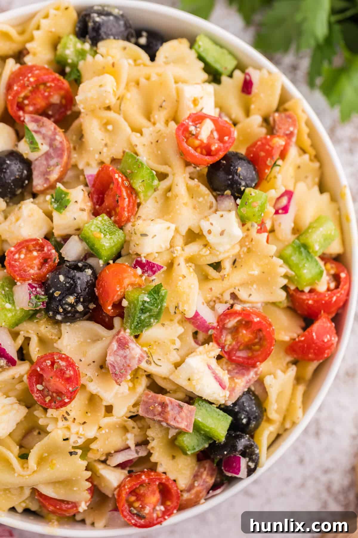 Close-up shot of the Italian pasta salad in a white bowl, showcasing the vibrant colors and varied textures of the ingredients.