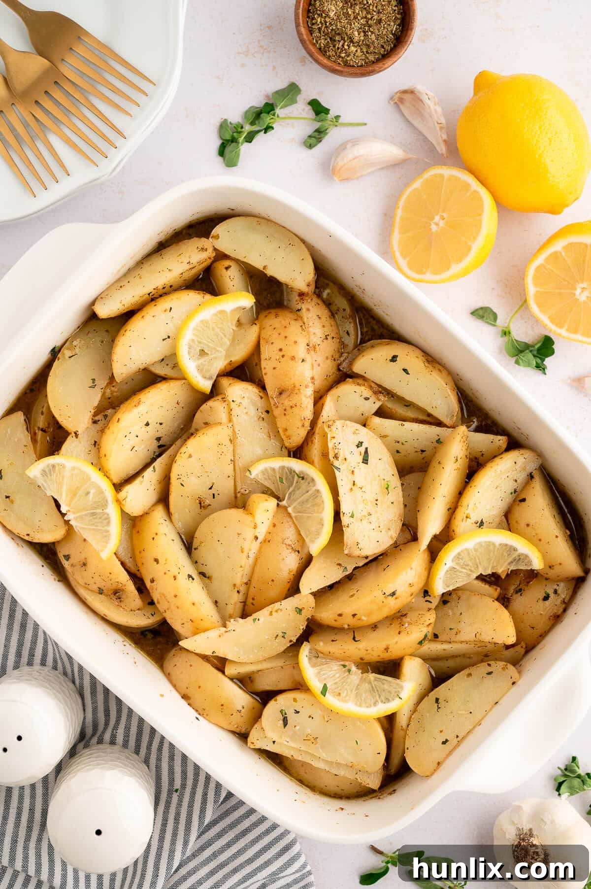 A pan of golden, crispy lemon roasted potatoes with fresh herbs as garnish.
