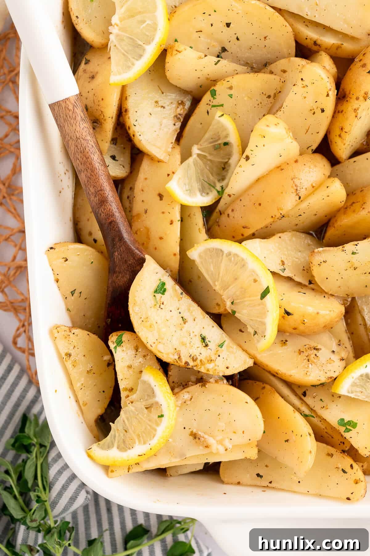 A serving pan filled with lemon roasted potatoes and a wooden serving spoon.