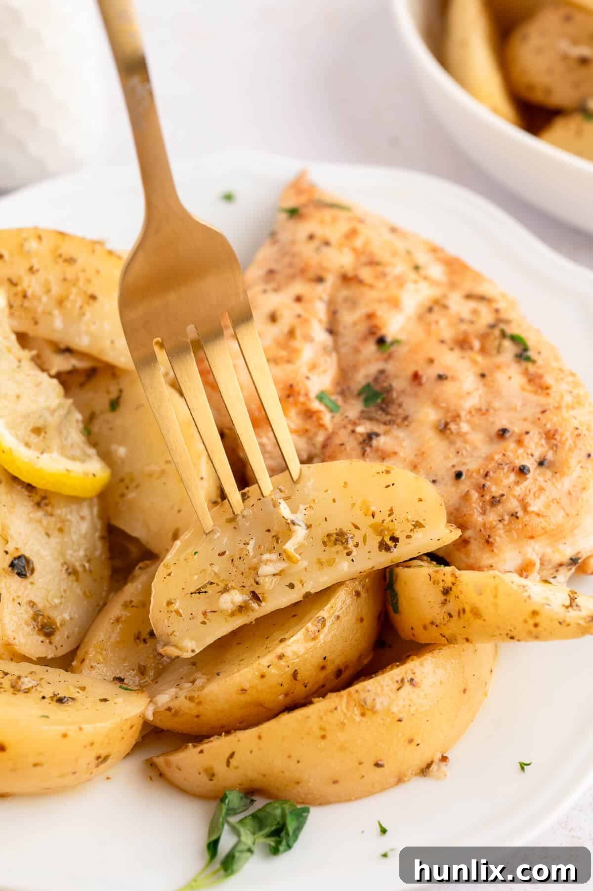 A single serving of lemon roasted potatoes on a plate with a fork, ready to be enjoyed.