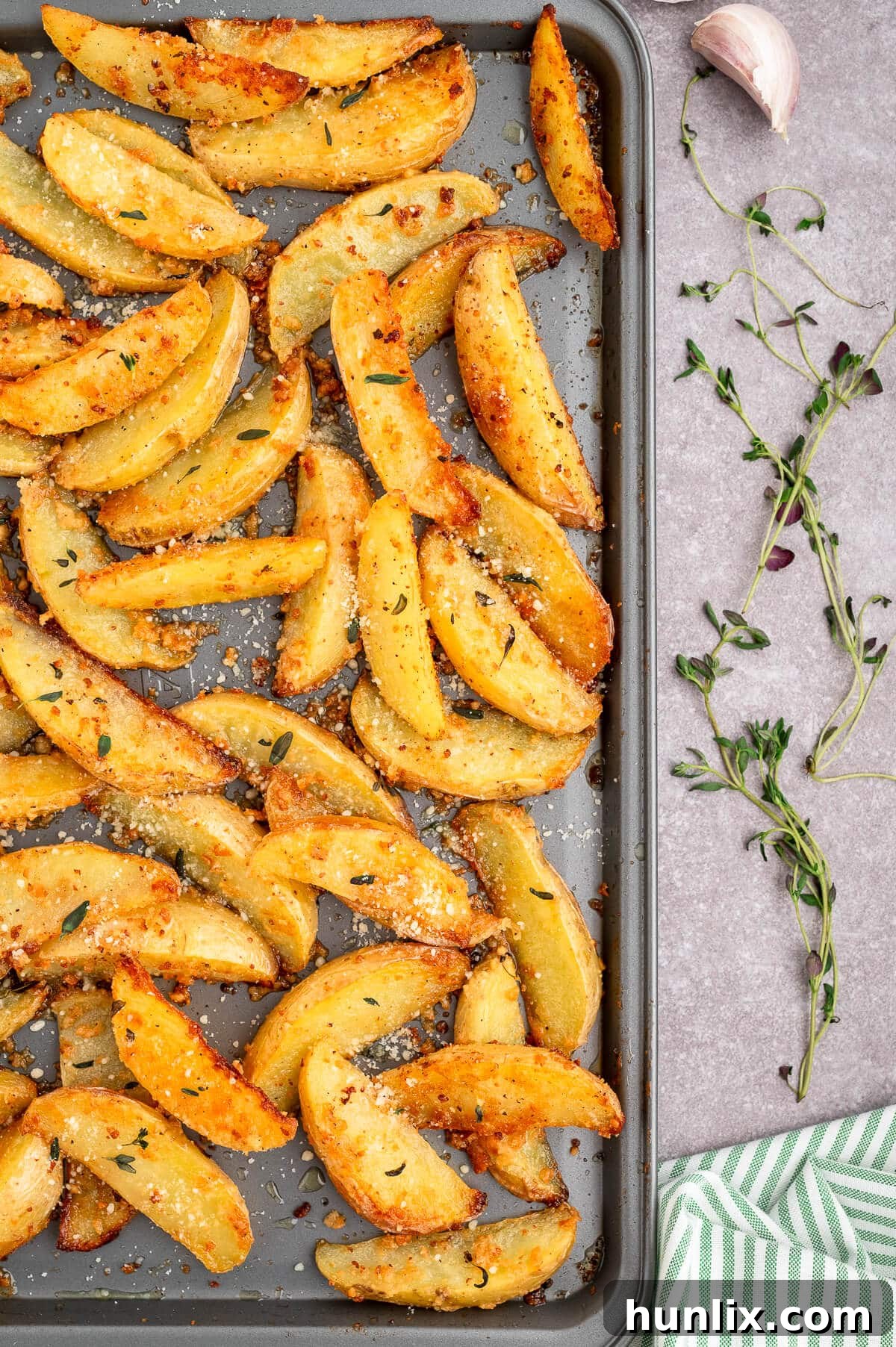 A tray of Parmesan thyme roasted potatoes, perfectly browned and seasoned, fresh from the oven and ready to be served.