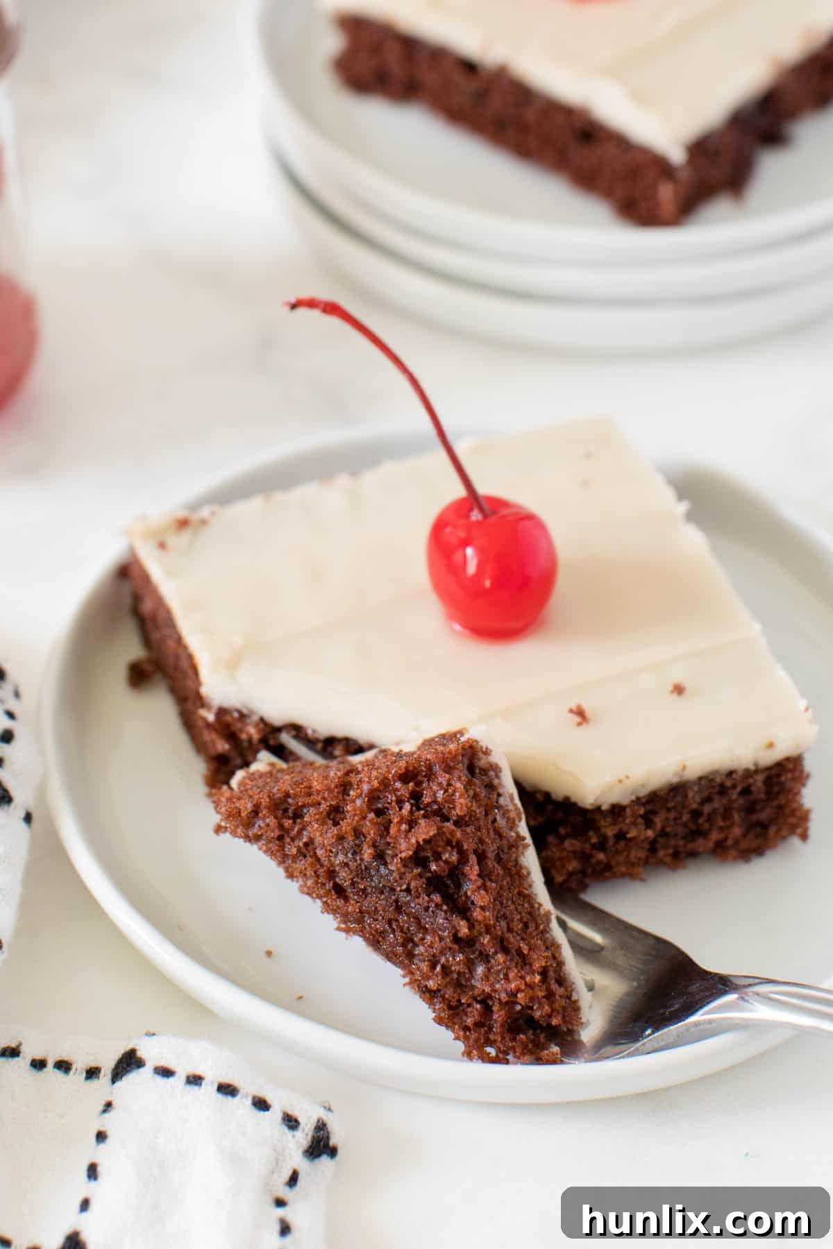 A close-up of a slice of root beer float sheet cake on a plate, with a fork digging into the tender cake, ready for a bite.
