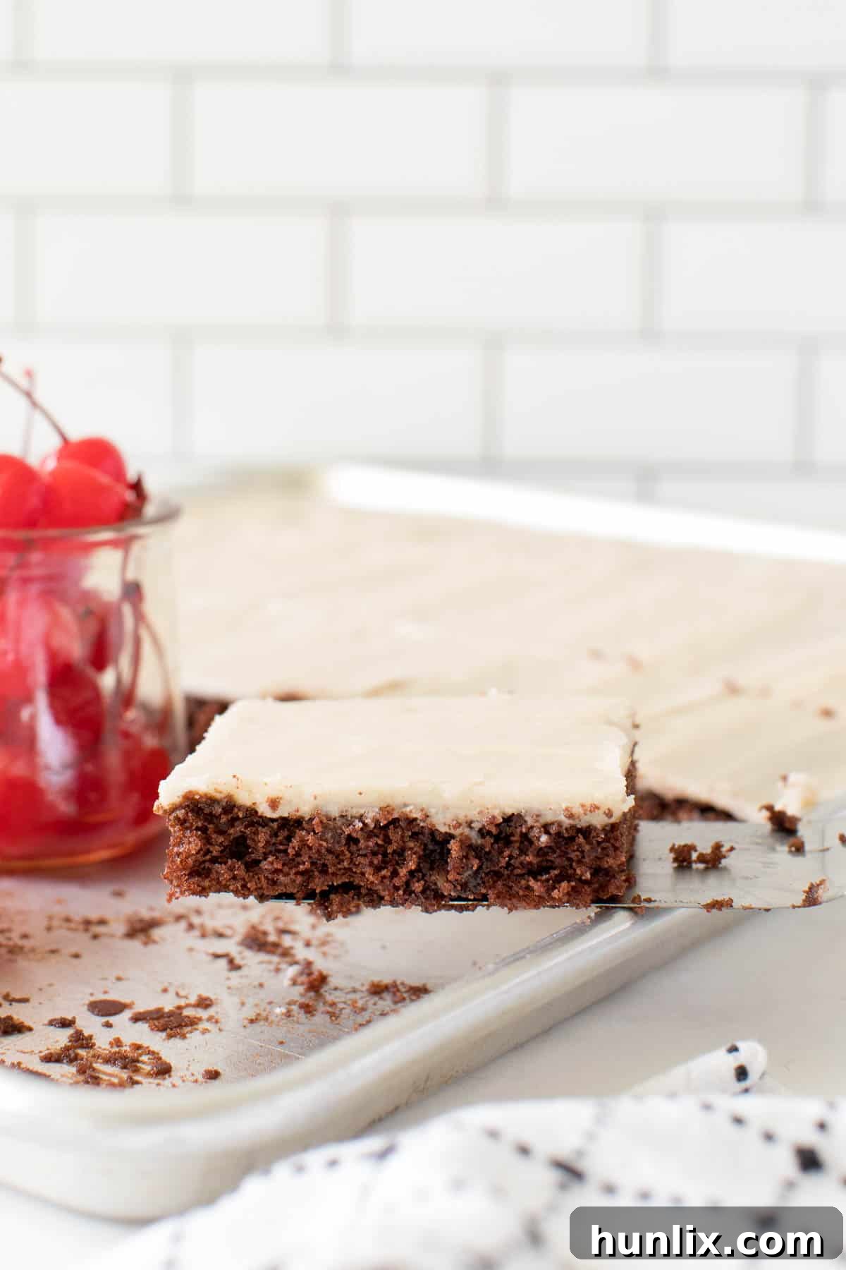 A slice of root beer float sheet cake being lifted from the pan with a serving spatula, ready to be placed on a plate.