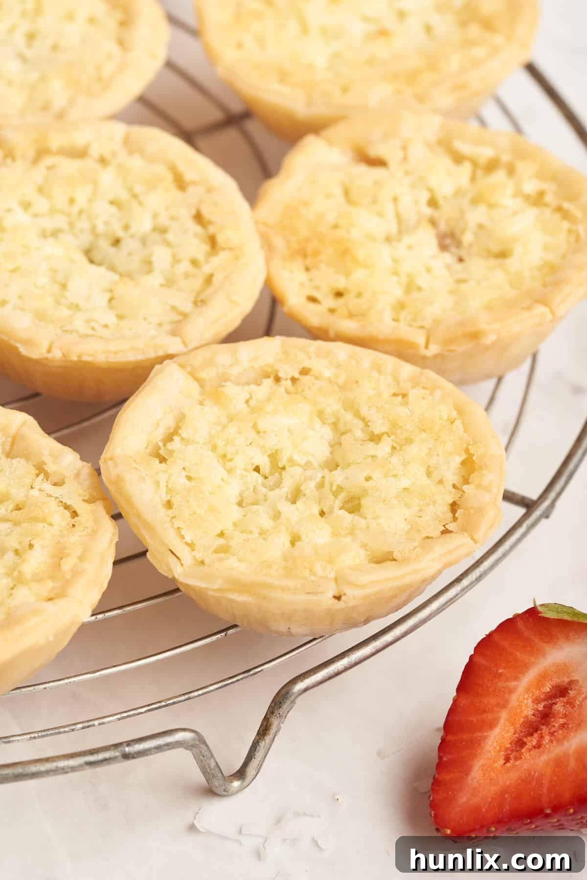Freshly baked strawberry coconut tarts cooling on a wire rack, ready to be enjoyed.