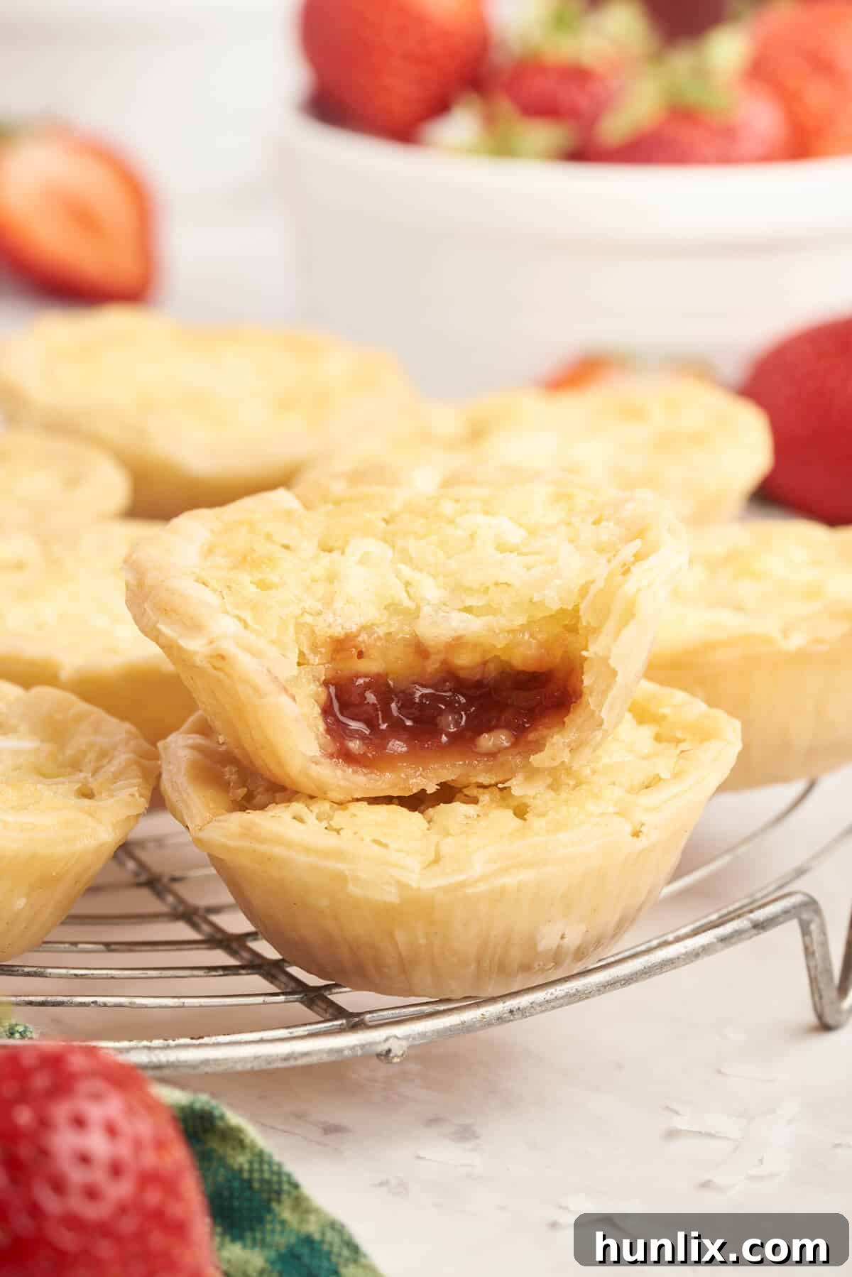 A collection of baked strawberry coconut tarts artfully arranged on a cooling rack.