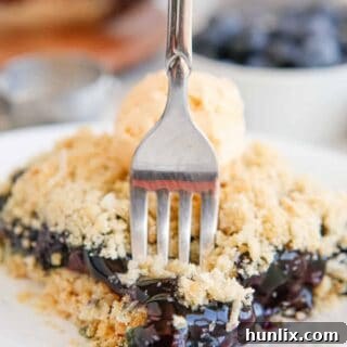 Blueberry Brittle Bake 11 Blueberry crackle cake piece on a plate with a fork in it.