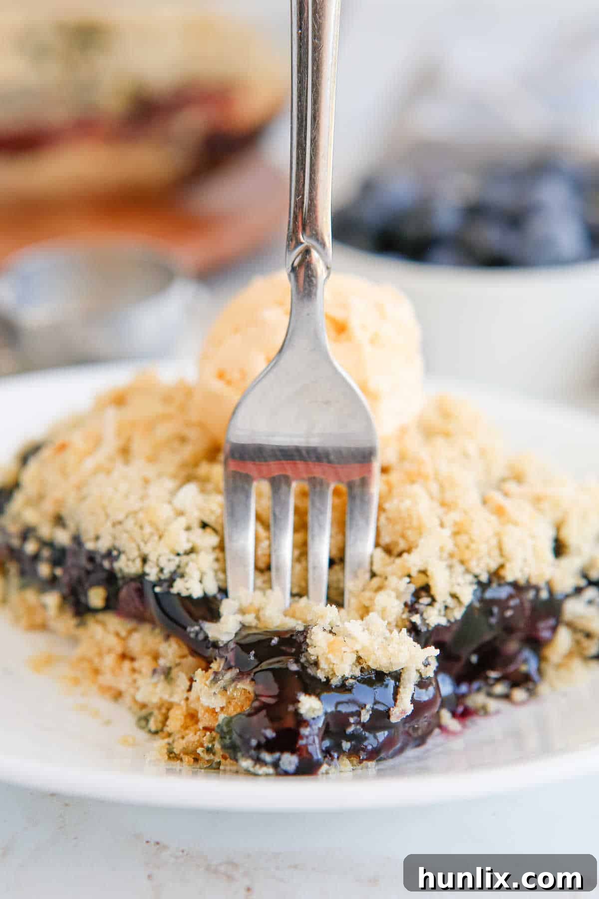 Blueberry Brittle Bake 9 A fork piercing into a piece of Blueberry Crackle Cake, showing the soft, moist interior and crunchy exterior.