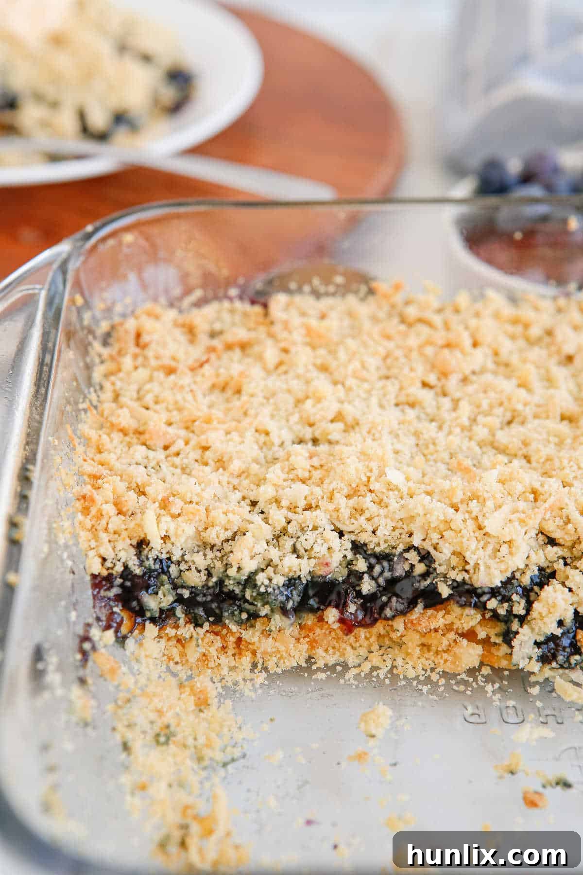 Blueberry Brittle Bake 10 A baking pan filled with Blueberry Crackle Cake, with several slices already removed, showing the golden crust and fruity interior.