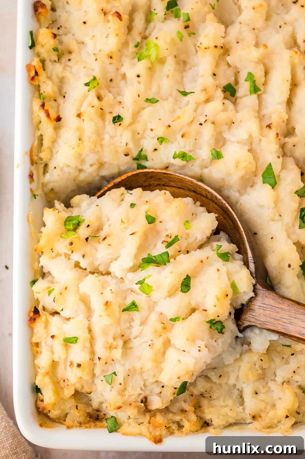 Golden Turnip Delight 6 A rustic white pan filled with turnip casserole, with a wooden spoon resting inside, highlighting its readiness.