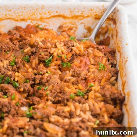 A Cabbage Roll Casserole in a dish with a serving spoon, illustrating the recipe.