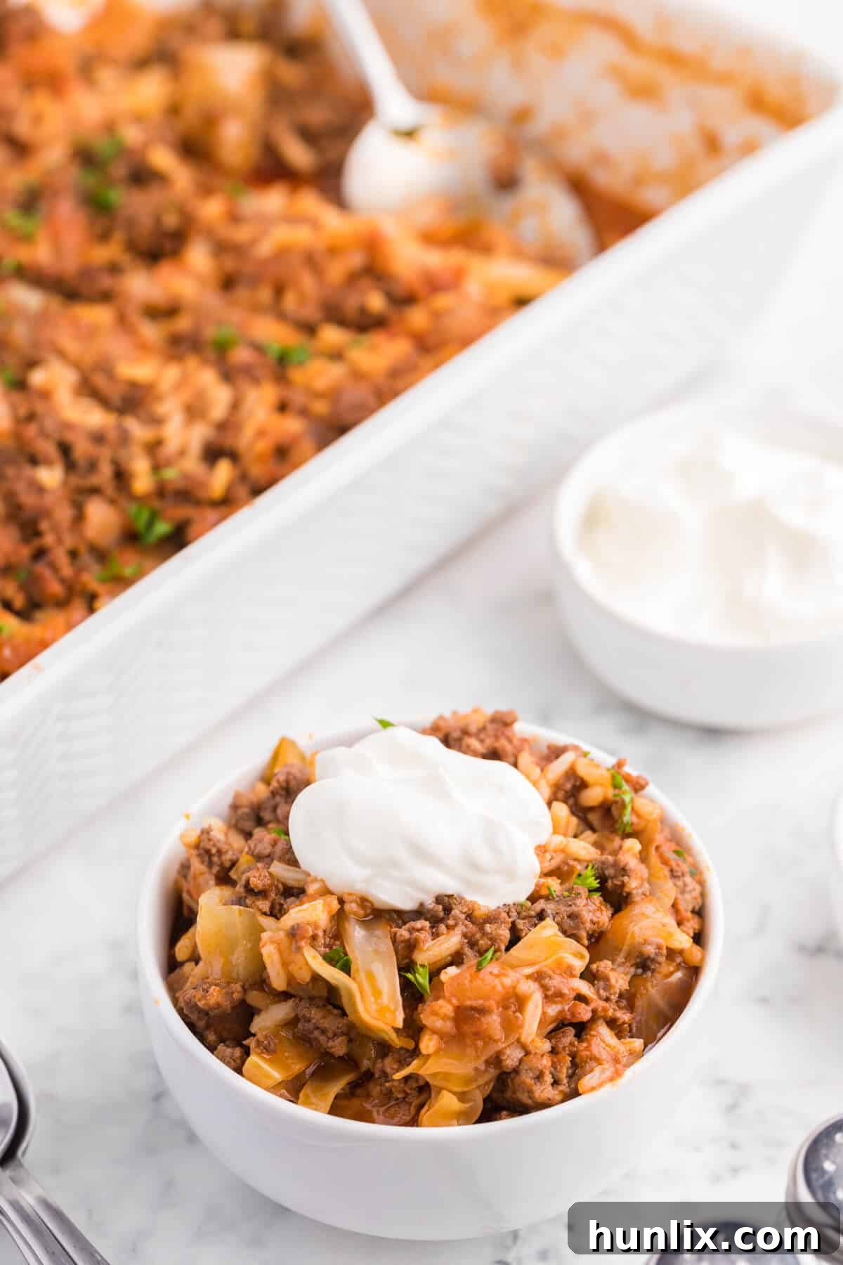 A bowl of Cabbage Roll Casserole topped generously with sour cream, emphasizing its creamy texture and comforting appeal.