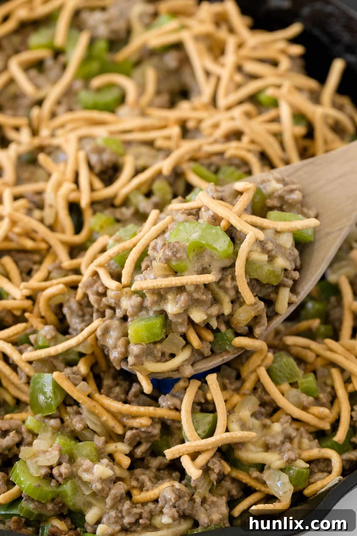 One-Pan Chow Mein 2 A steaming Chow Mein Skillet in a cast iron pan with a wooden serving spoon, ready to be enjoyed.