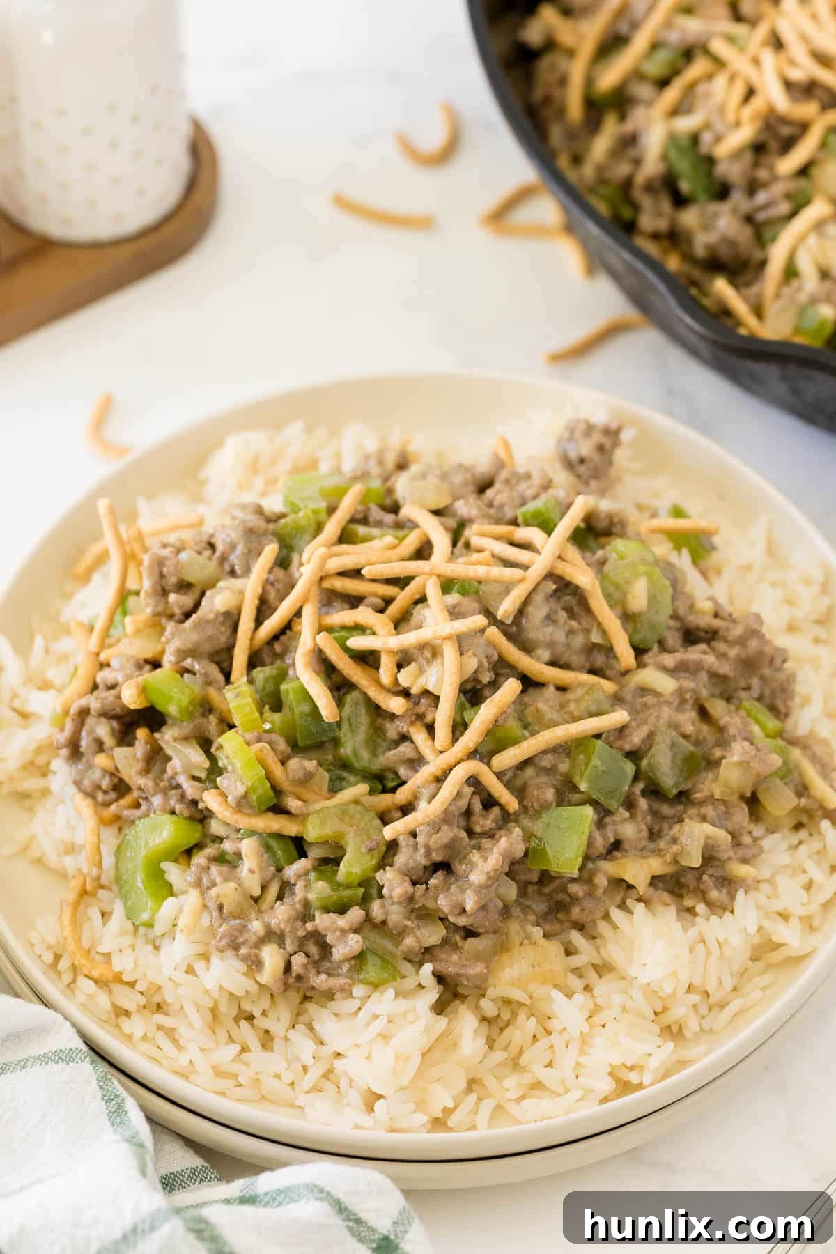 One-Pan Chow Mein 6 A portion of Chow Mein Skillet served over a bed of fluffy white rice on a plate, garnished with fresh green onions.
