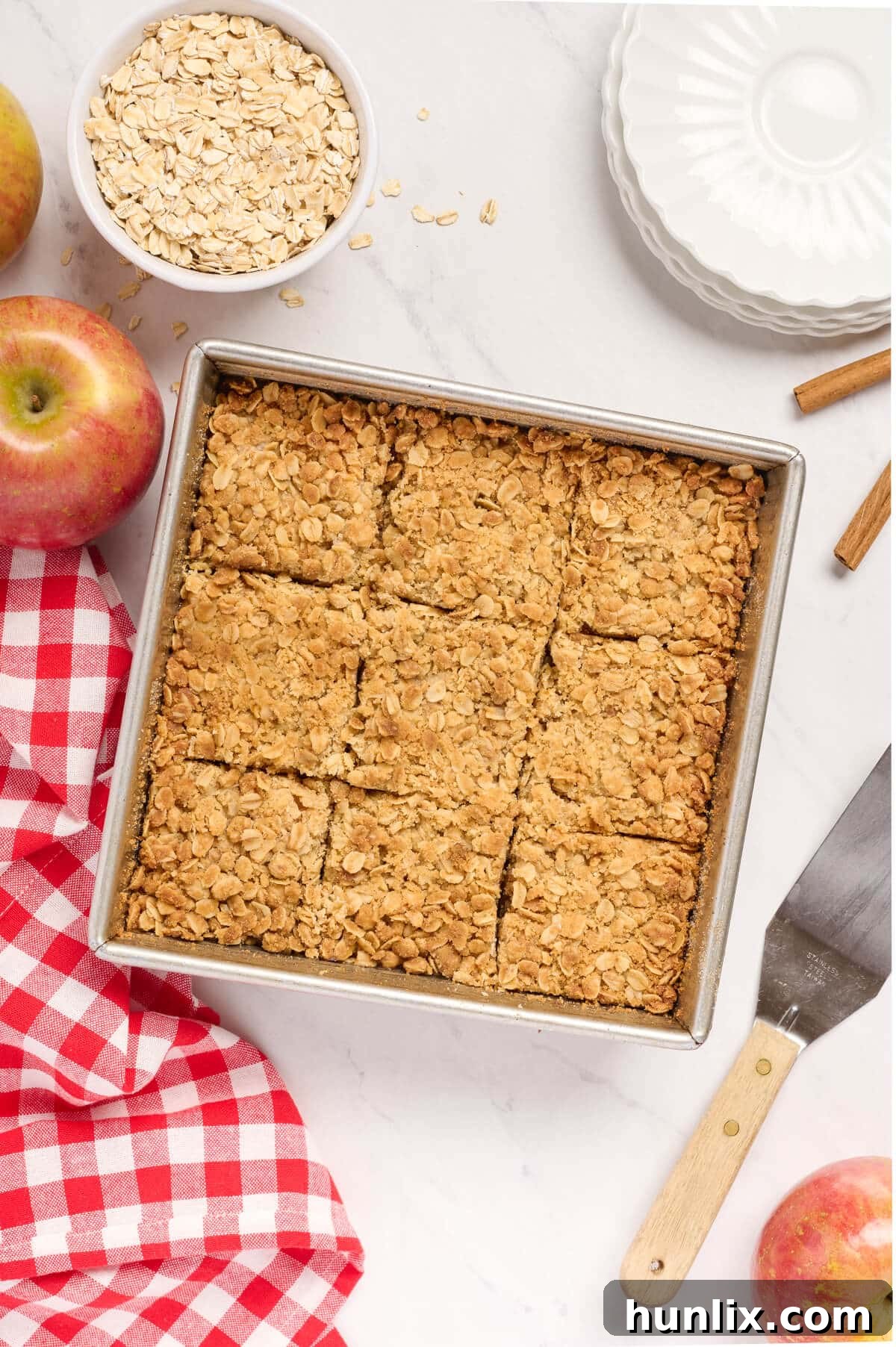 A baking pan filled with golden-brown apple crisp bars, neatly scored into individual servings, showcasing the finished dessert.