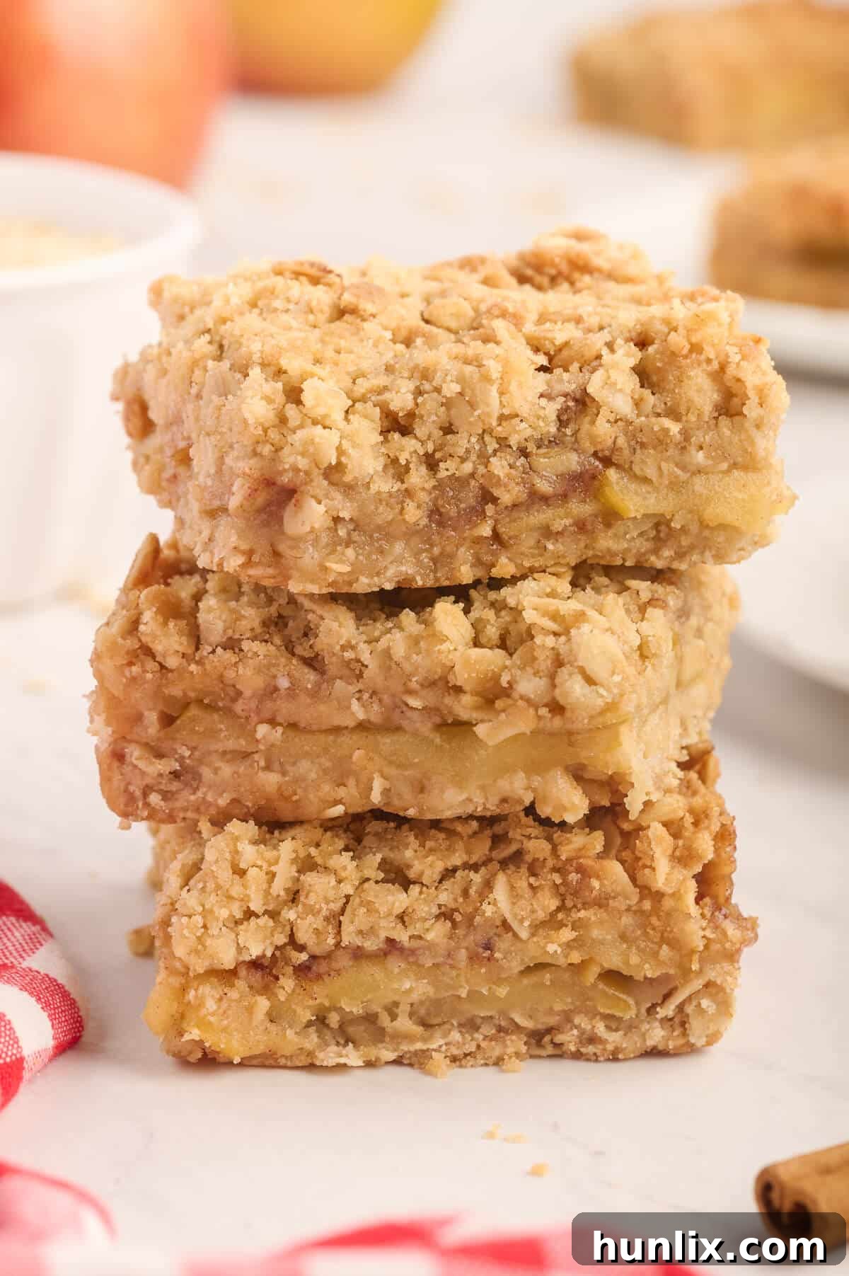 A stack of perfectly baked and cooled apple crisp bars piled on a white plate, showcasing their inviting golden color.