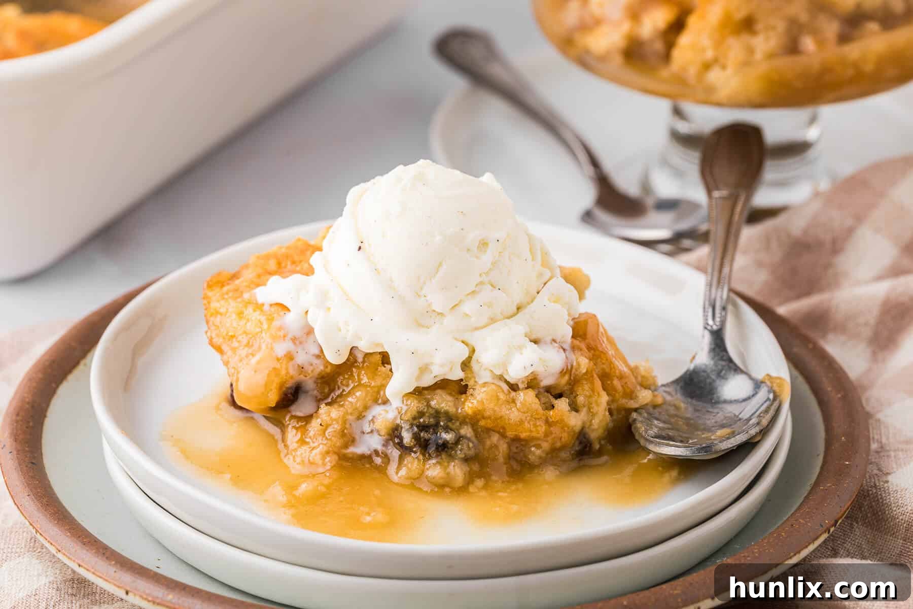 A slice of Radio Pudding served on a plate with a scoop of vanilla ice cream, ready to eat.