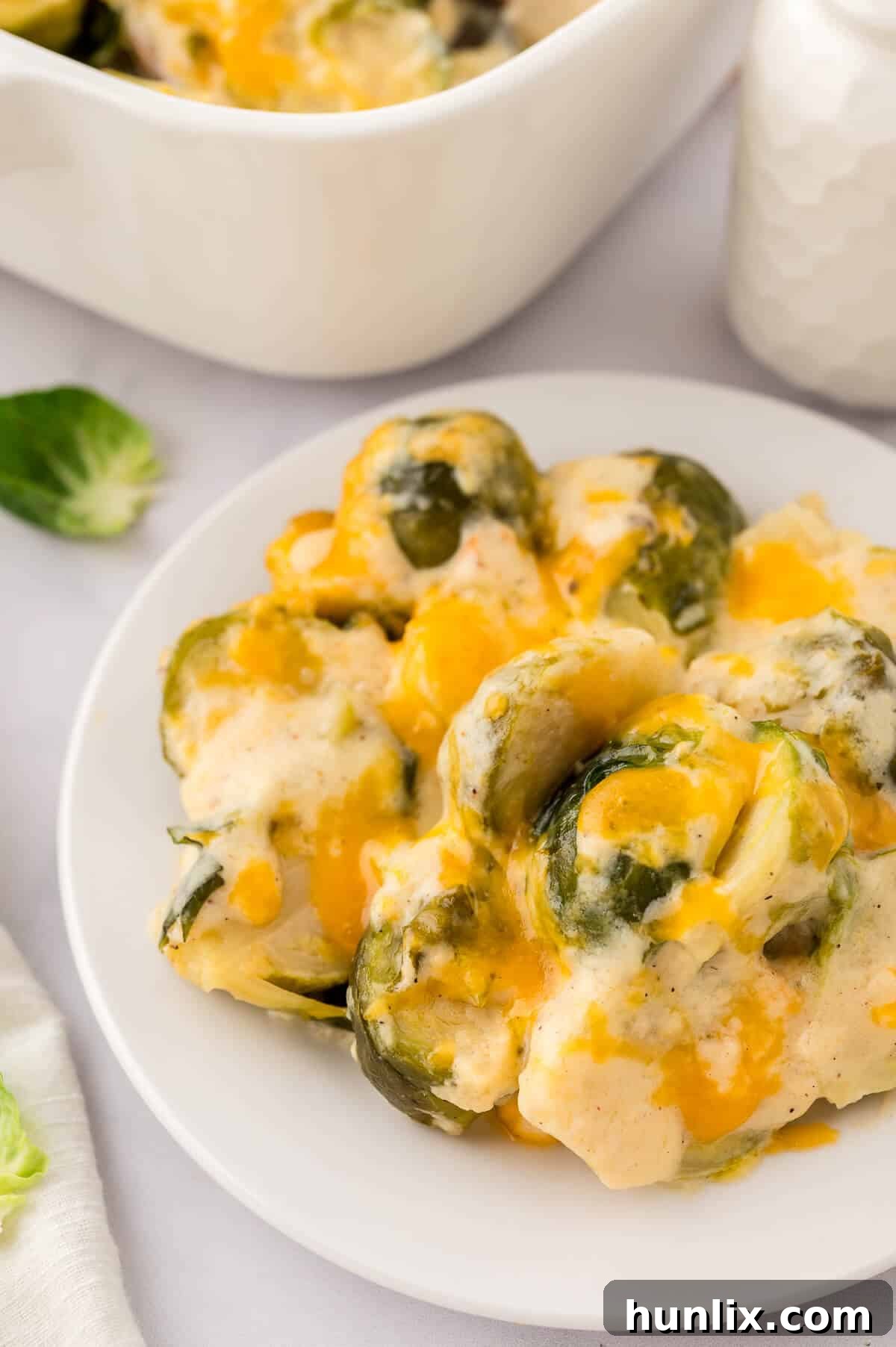 A pristine white plate showcasing a perfectly portioned serving of cheesy Brussels sprouts, ready to be enjoyed.