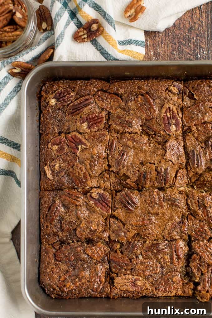 Maple pecan squares freshly baked in a pan, glistening with the sweet topping.