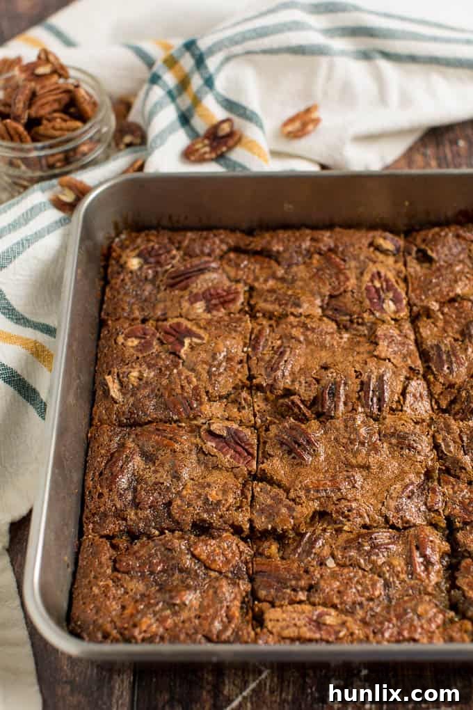 Close-up of baked maple pecan squares in a pan, highlighting the glossy, nutty topping.