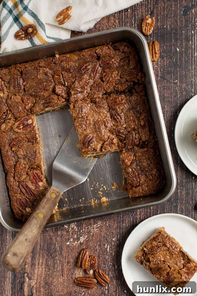 A single maple pecan square being lifted from the pan with a spatula, showing its gooey texture.