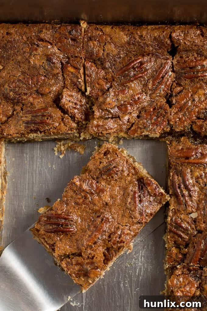 A single maple pecan bar on a spatula, ready to be served from the baking pan.