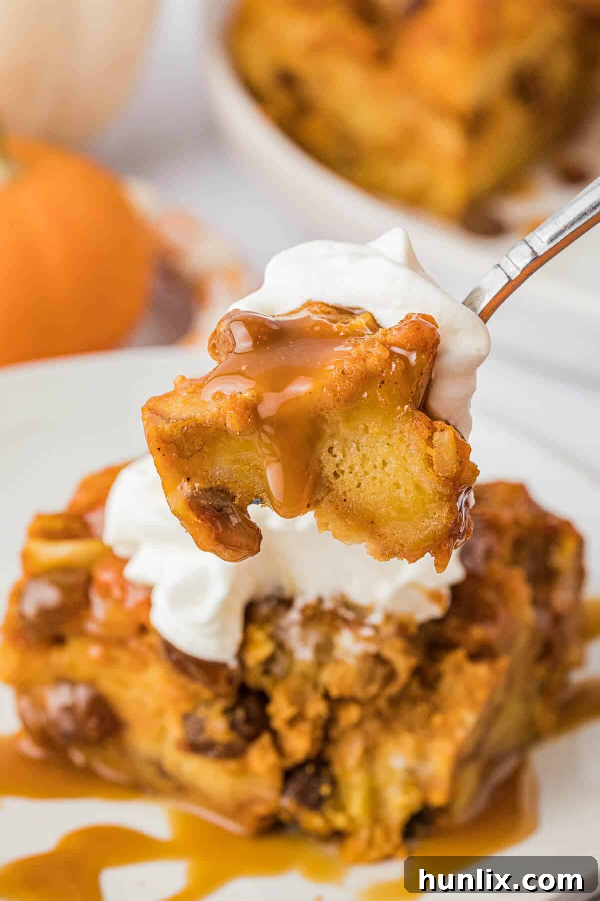 A close-up view of a fork holding a piece of moist pumpkin bread pudding, showcasing its tender texture and inviting warmth.