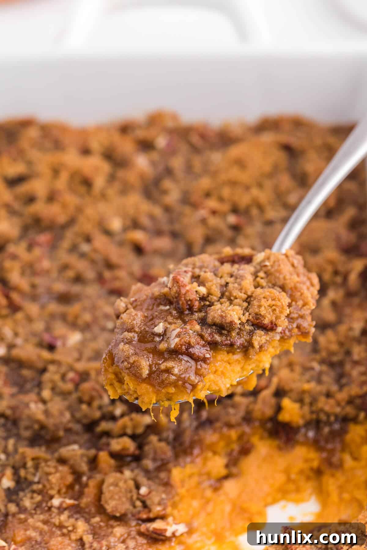 Golden Sweet Potato Delight 7 A serving of sweet potato casserole on a spoon, showing its creamy texture and pecan topping.