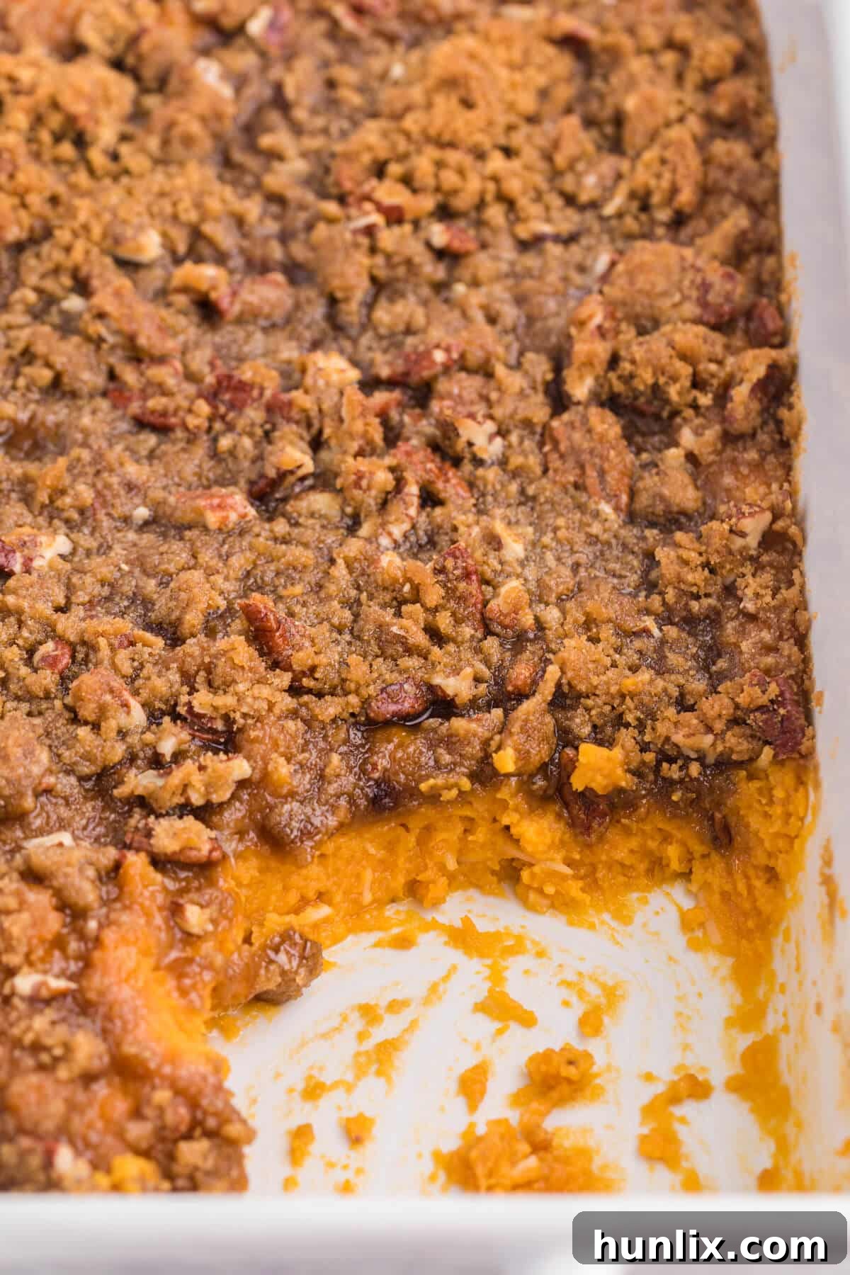 Golden Sweet Potato Delight 8 A sweet potato casserole with a scoop removed, showing the creamy interior and crispy topping.