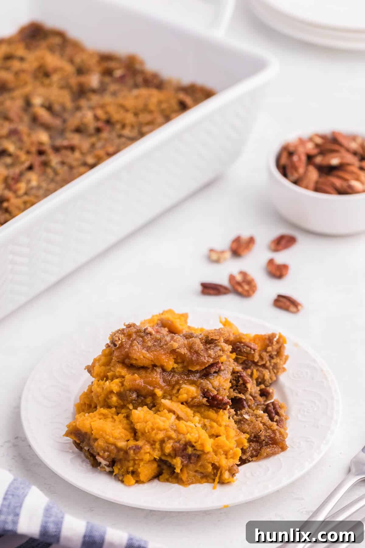 Golden Sweet Potato Delight 9 A slice of sweet potato casserole on a white plate, showing its layers.