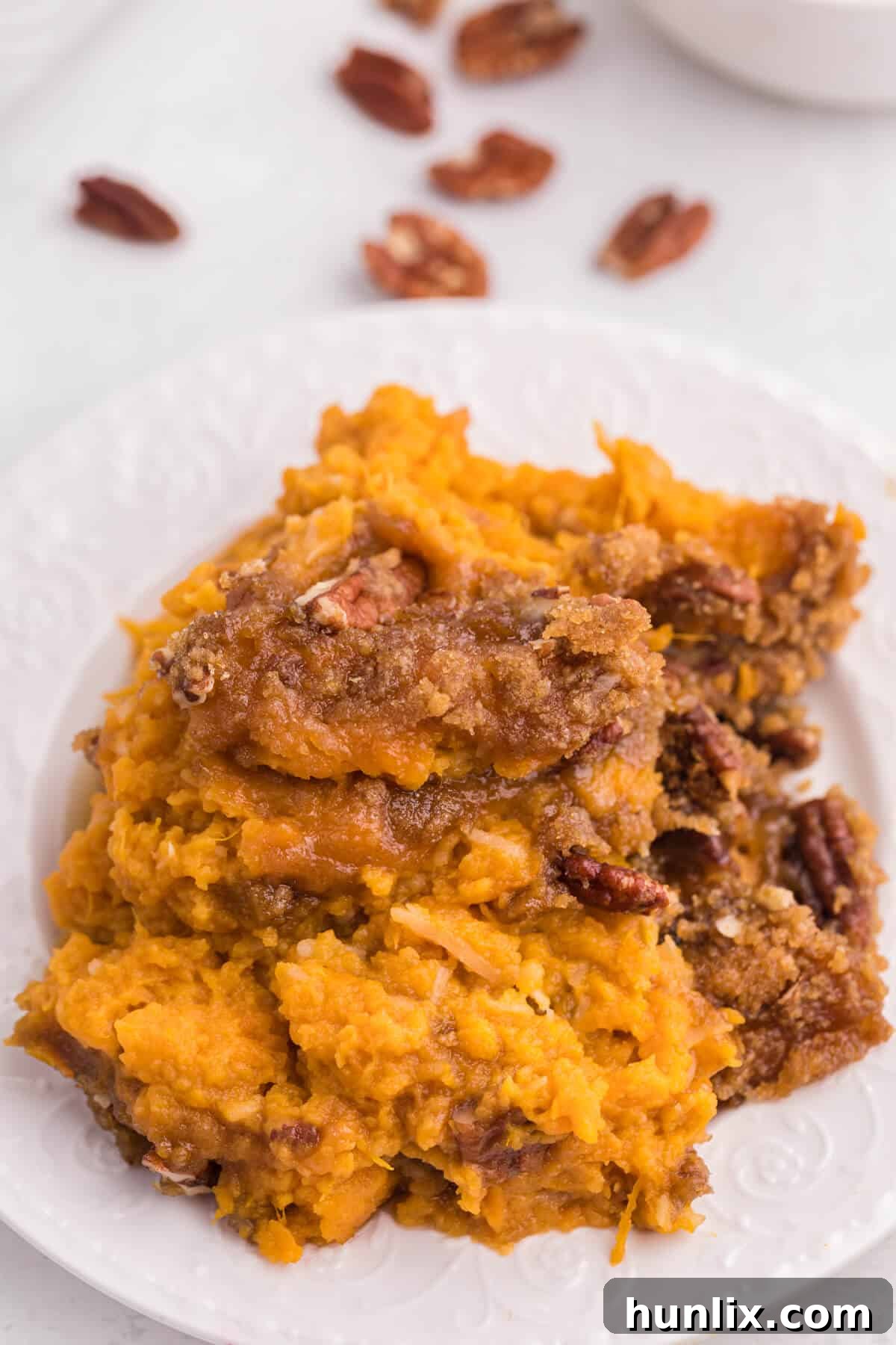 Golden Sweet Potato Delight 10 A serving of sweet potato casserole on a white plate with a fork.