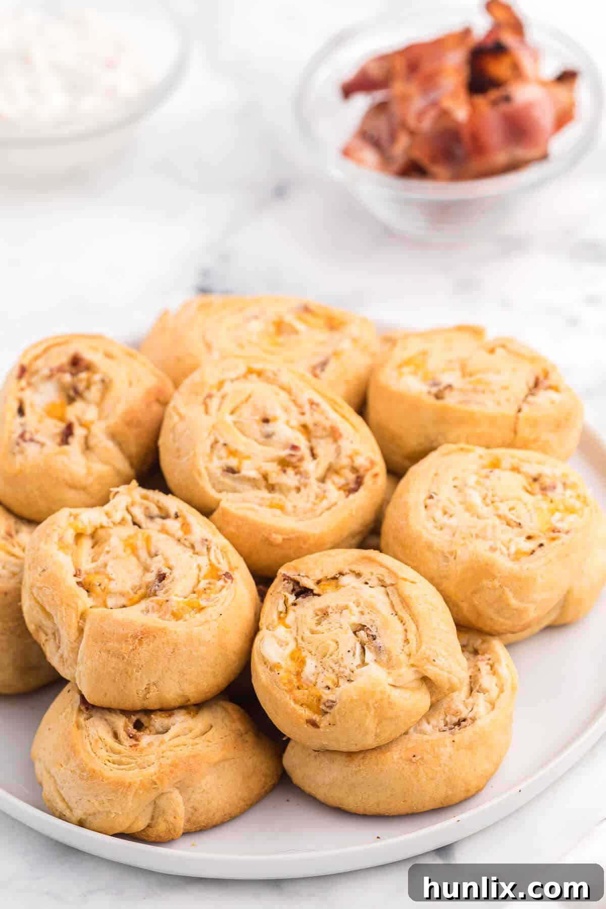 Close-up of golden brown Cheesy Bacon Pinwheels, baked to perfection, showcasing the crispy bacon and melted cheddar cheese peeking out from the flaky crescent roll layers.