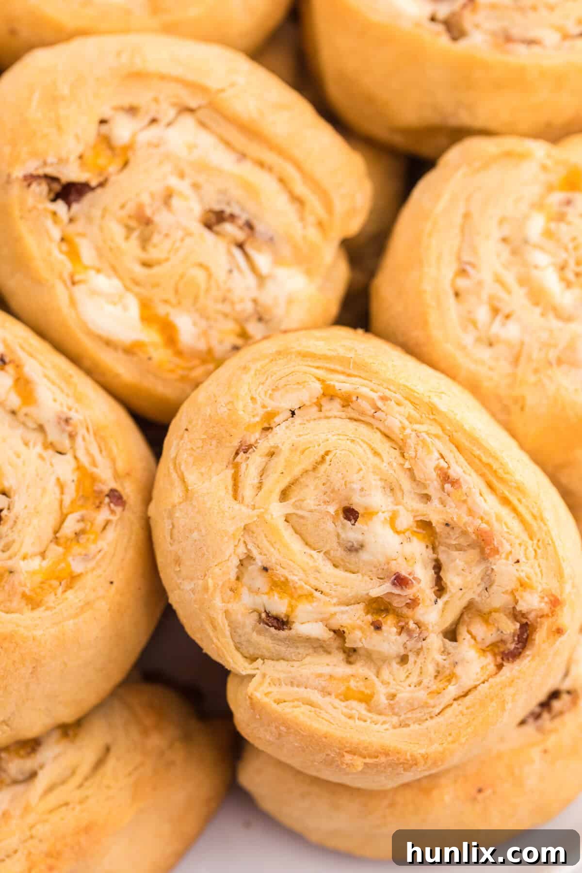 A baking sheet filled with freshly sliced Cheesy Bacon Pinwheels, ready to go into the oven, showcasing the vibrant filling before baking.