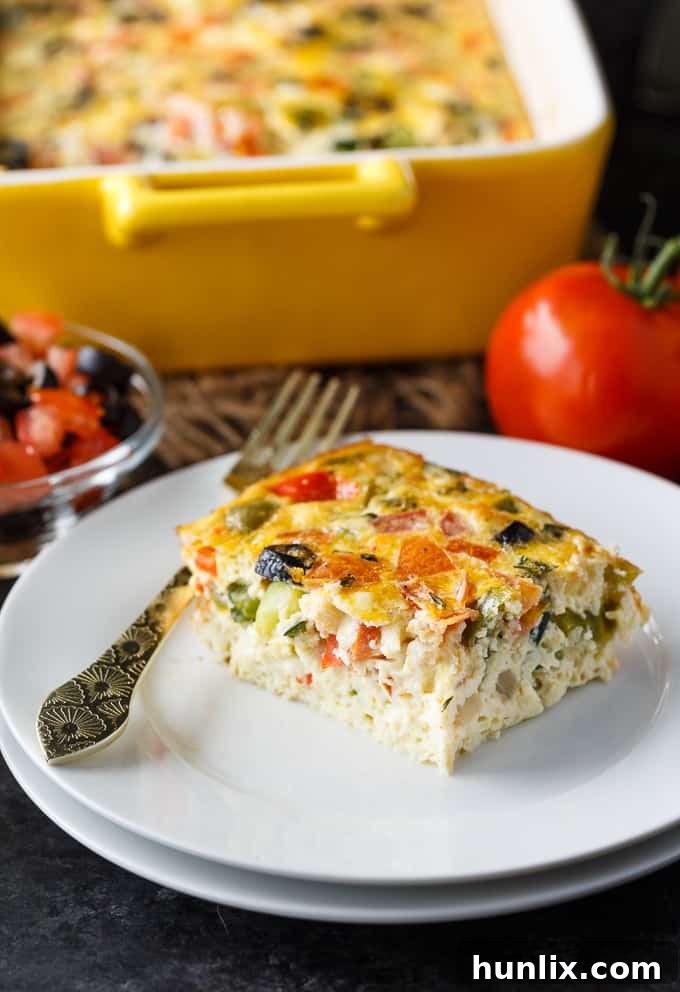 Mediterranean Sunrise Bake 5 A slice of Mediterranean Brunch Bake on a plate, showcasing layers of egg, vegetables, and feta cheese.