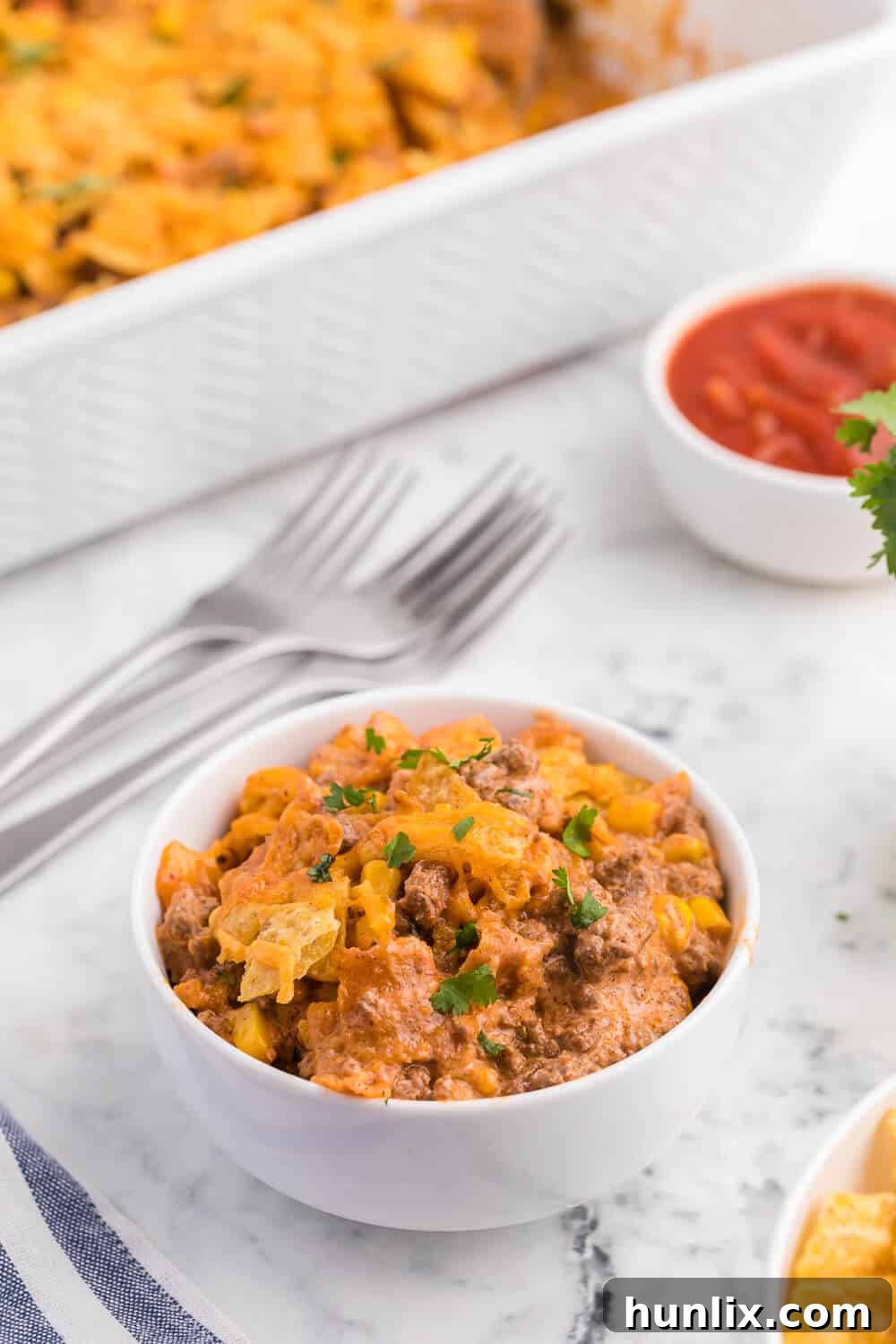 Fiesta Beef Nacho Bake 5 Beef nacho bake served in a white bowl, close up, showing melted cheese and beef.