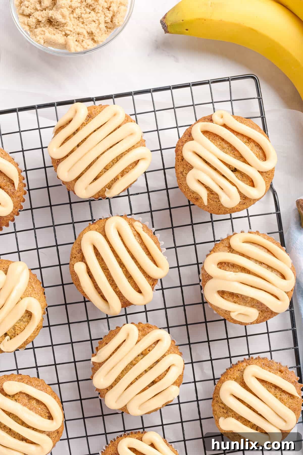 Golden brown caramel banana muffins cooling on a wire rack, showcasing their moist texture and shiny caramel topping.