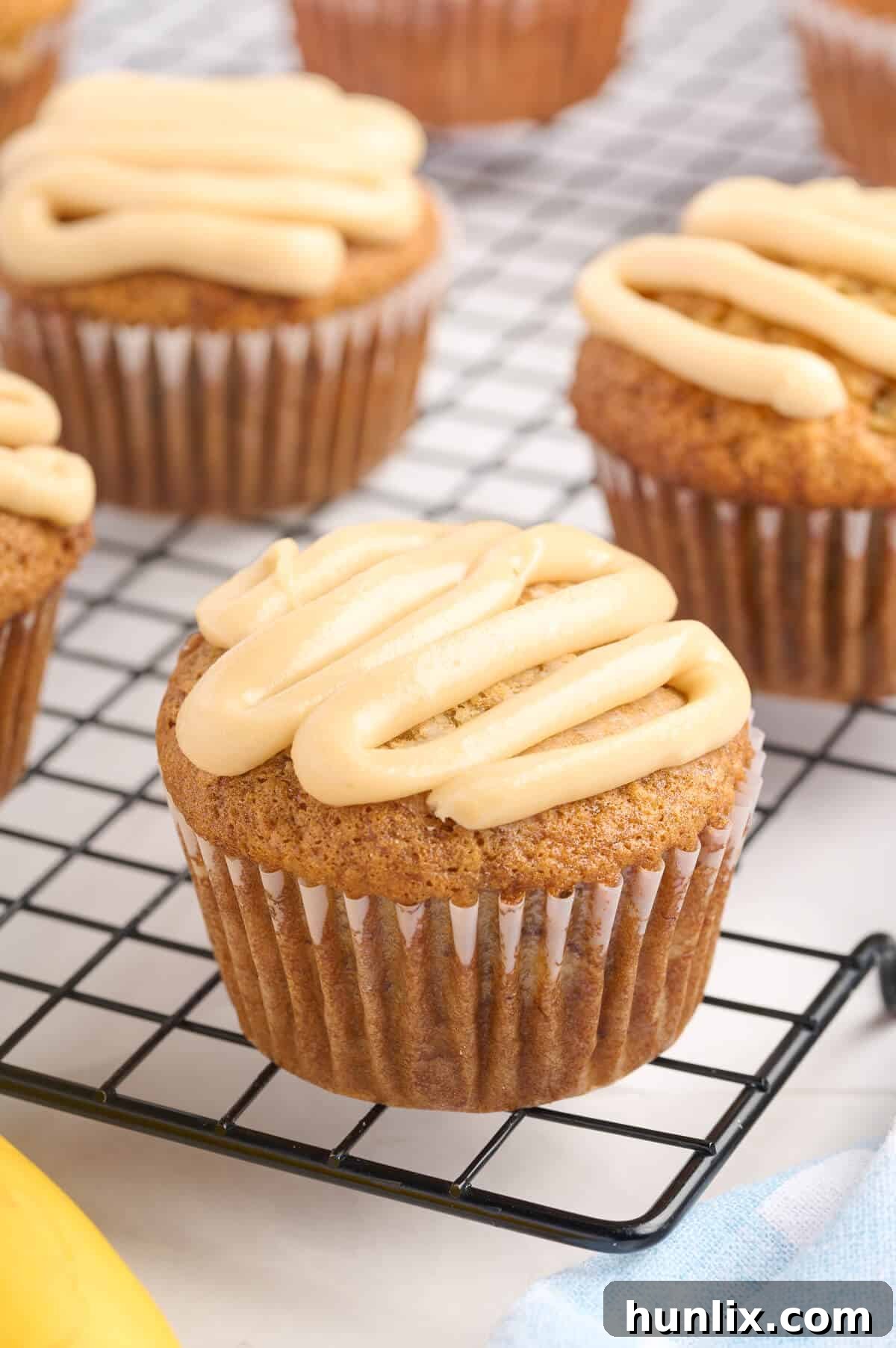 A single caramel banana muffin placed on a wire rack, highlighting its golden exterior and tempting caramel swirl.