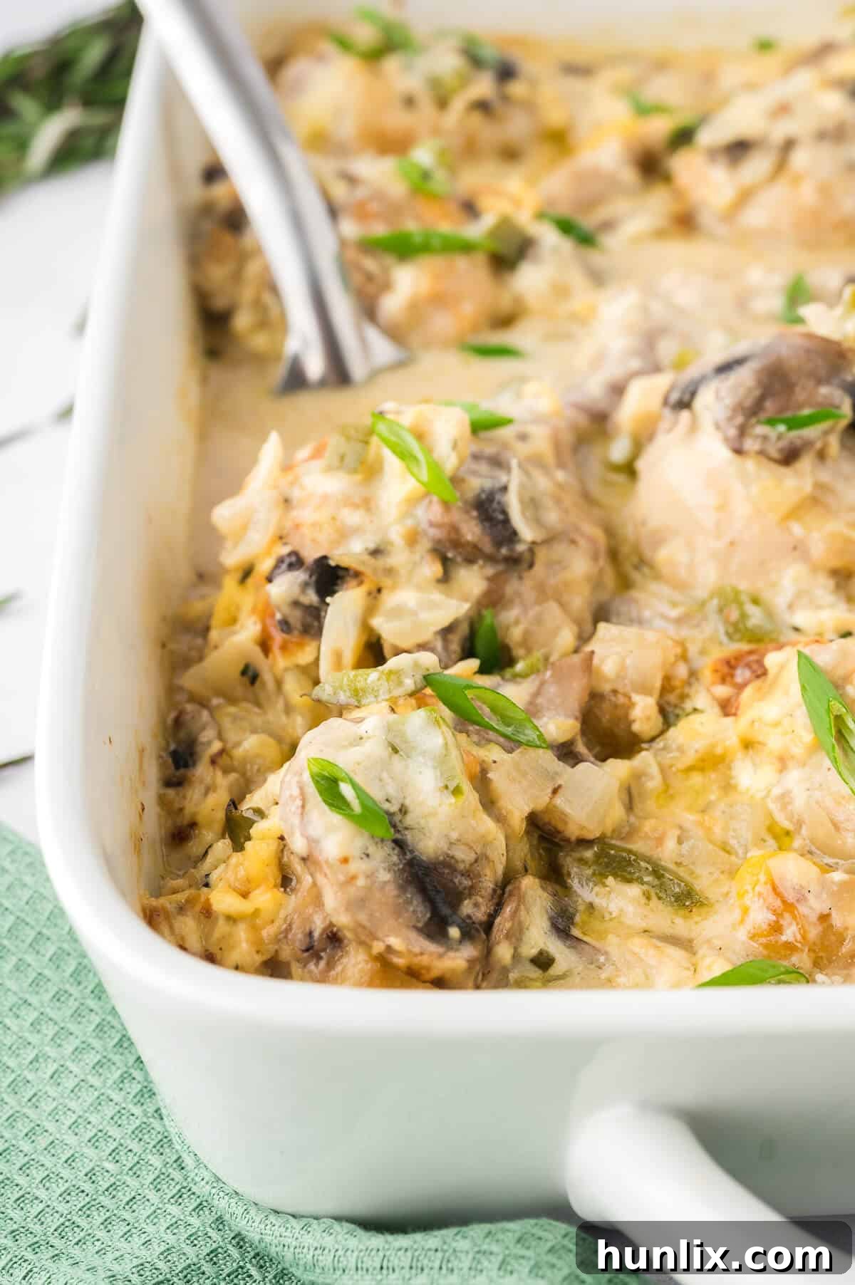 Tender Chicken in Rich Gravy 2 Golden-brown smothered chicken pieces generously coated in a rich, creamy gravy, nestled in a baking pan, ready to be served with a large serving spoon.