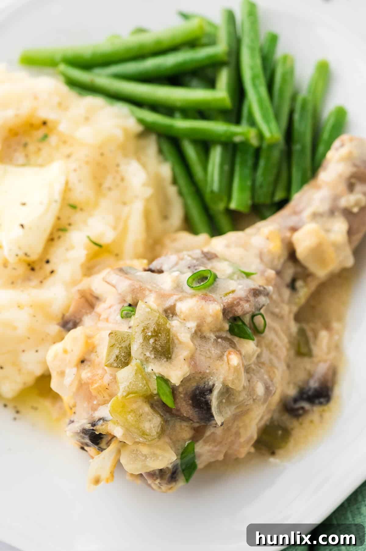 Tender Chicken in Rich Gravy 7 A plate featuring tender smothered chicken served alongside creamy mashed potatoes and vibrant green beans, showcasing a complete and comforting meal.
