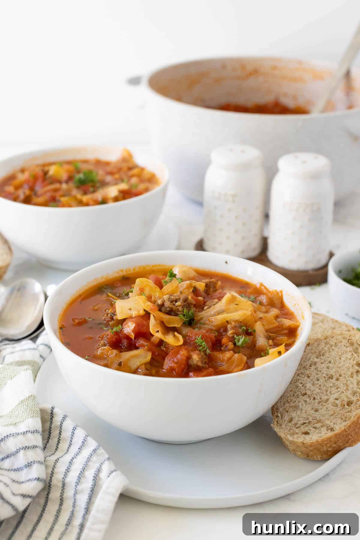 Hearty Sausage and Cabbage Soup 6 A serving of Sausage and Cabbage Soup in a white bowl, garnished fresh parsley.