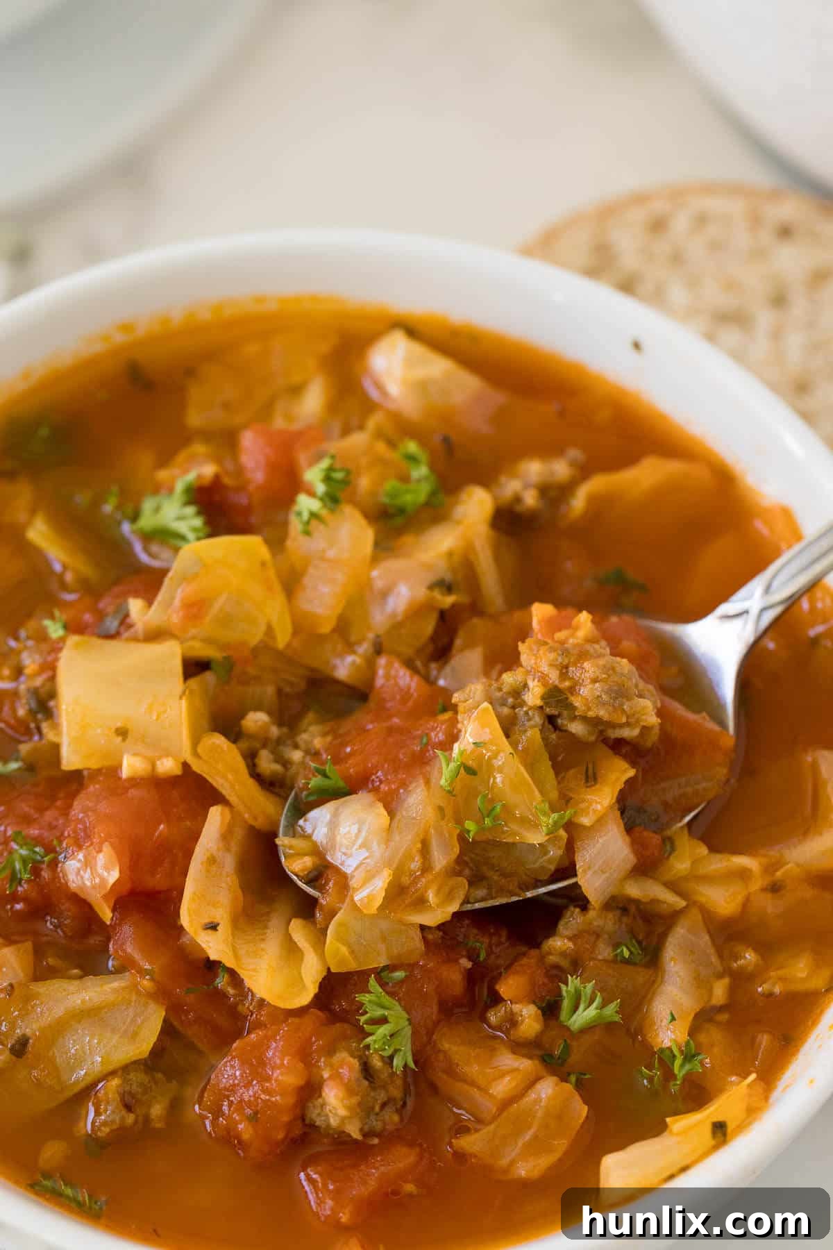 Hearty Sausage and Cabbage Soup 7 A close-up shot of Sausage and Cabbage Soup in a bowl with a spoon, highlighting its hearty texture.