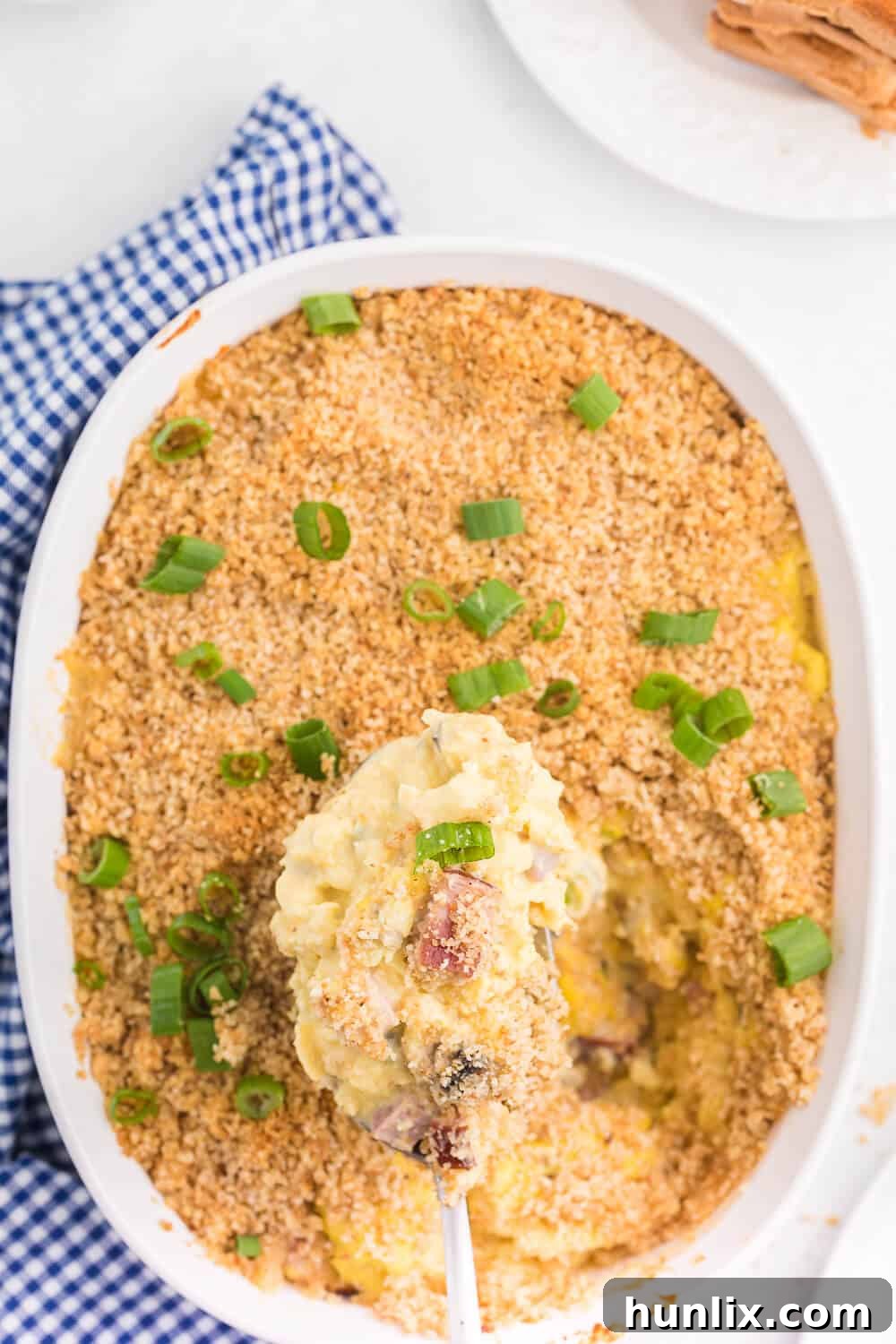 Sunrise Scramble Bake 2 A scoop of scrambled egg casserole on a serving spoon, showcasing its creamy texture and savory ingredients.