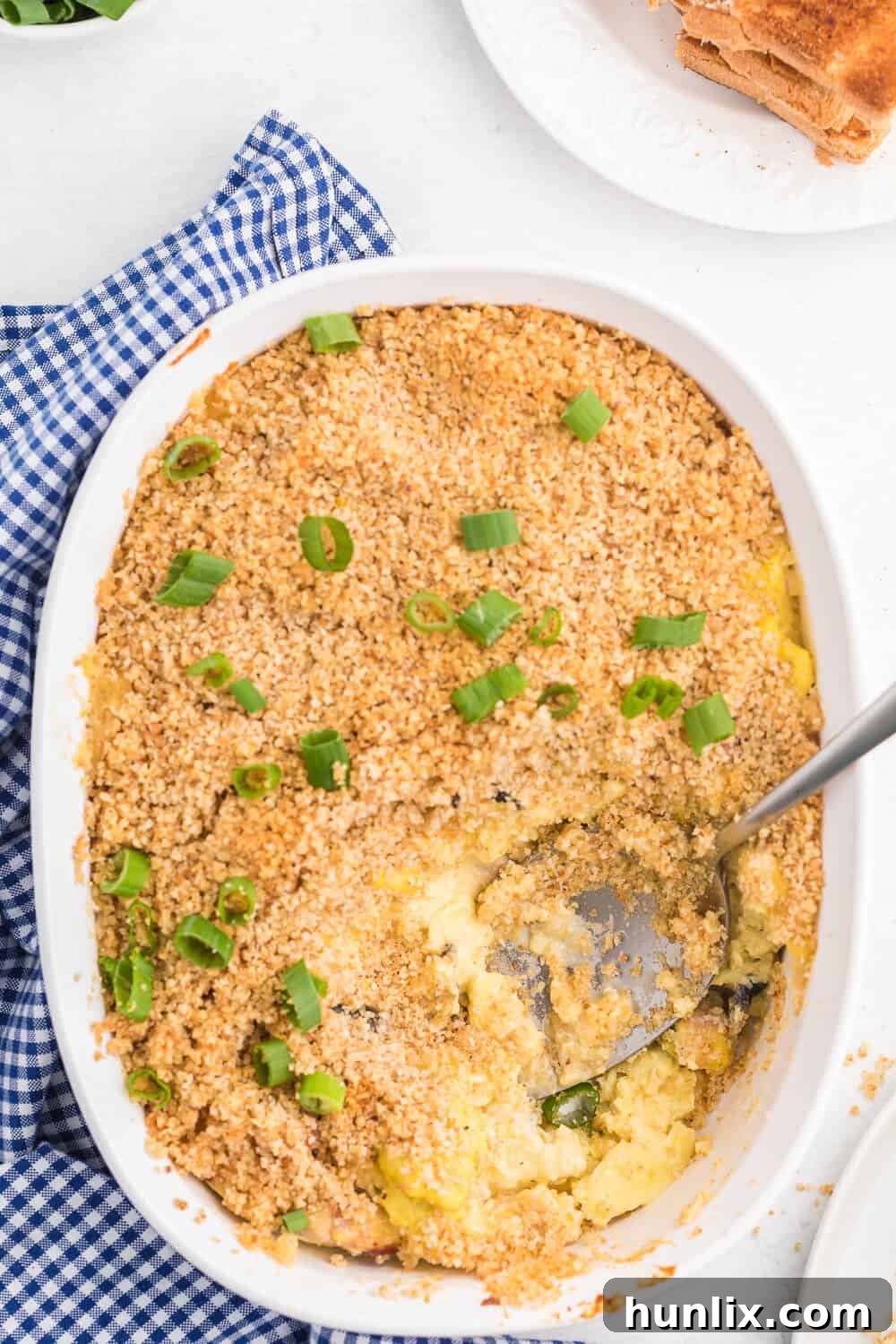 Sunrise Scramble Bake 3 The Scrambled Egg Casserole in a baking pan, with a serving spoon ready to scoop.