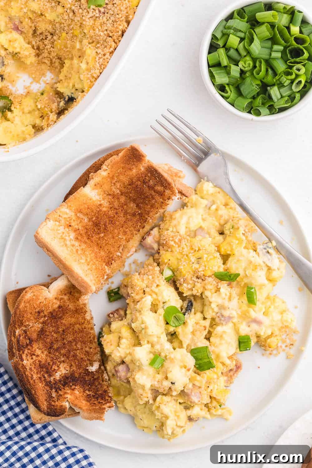 Sunrise Scramble Bake 4 A serving of scrambled egg casserole on a plate, accompanied by a piece of toast.