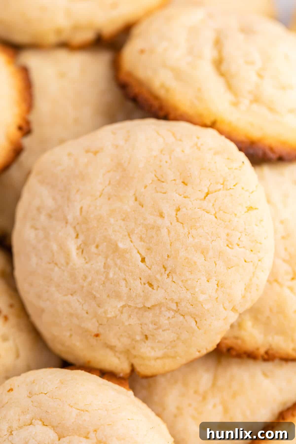 A generous pile of freshly baked cream cheese cookies on a white plate, ready to be served.