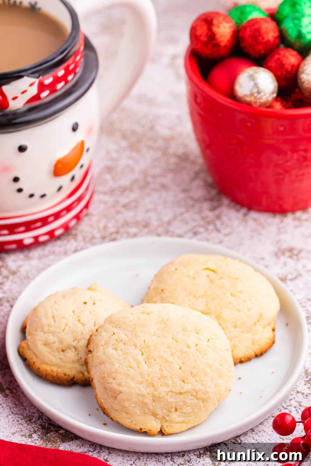 Three perfectly baked cream cheese cookies on a small white plate.