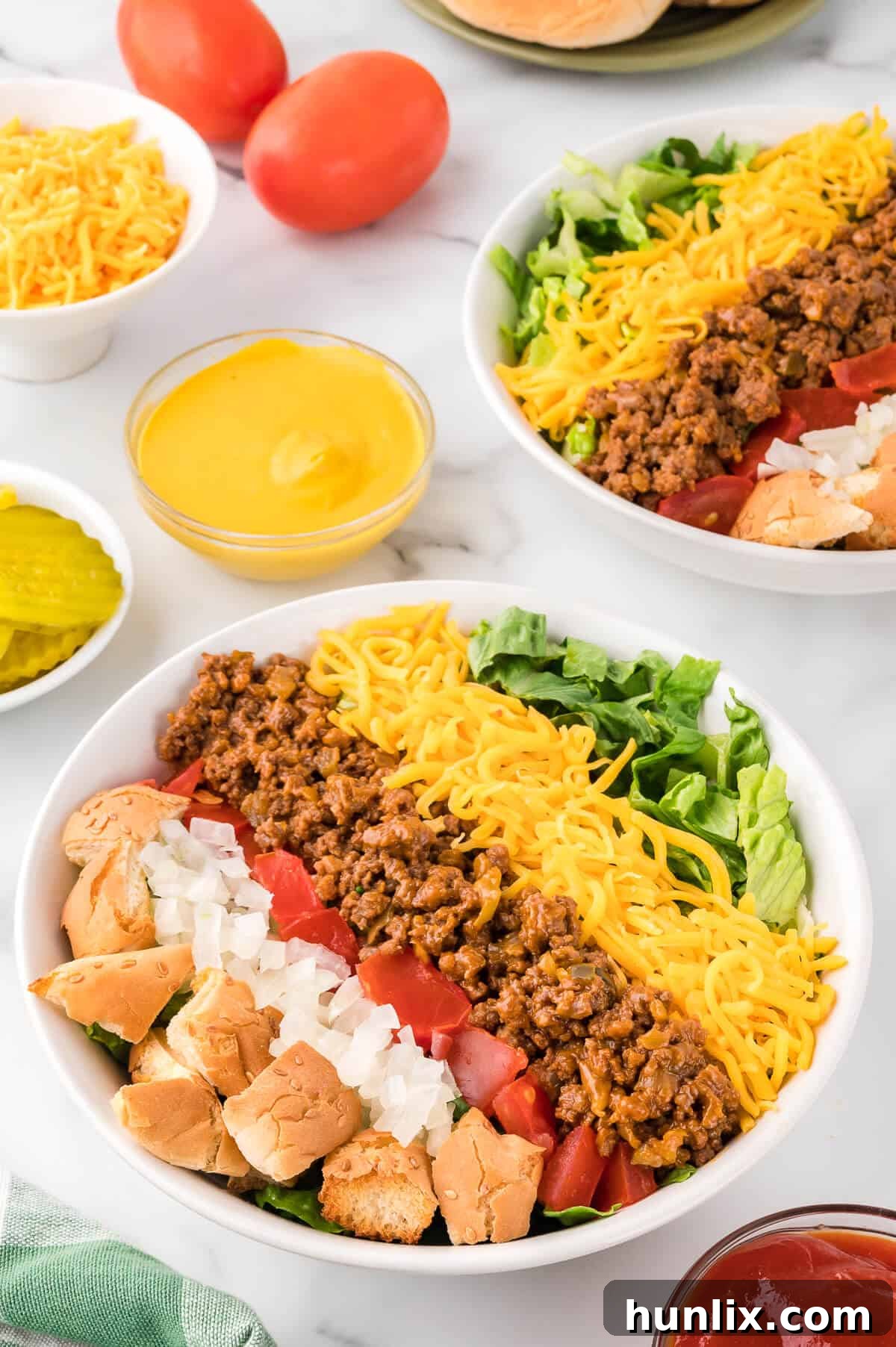 Cheeseburger in a Bowl 2 A vibrant bowl of homemade cheeseburger salad, featuring seasoned ground beef, melted cheese, fresh lettuce, juicy tomatoes, and crunchy bun croutons.